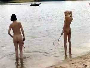 Slim bare little girls frolicking badminton on a sea beach.